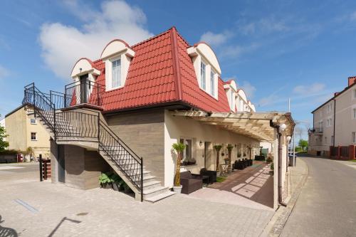 uma casa com um telhado vermelho e escadas numa rua em Wakacyjny Rewal / Dookoła Świata em Rewal