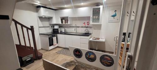 une petite cuisine avec des placards blancs et un escalier dans l'établissement LE COQUELICOT - centre ville, à Cahors