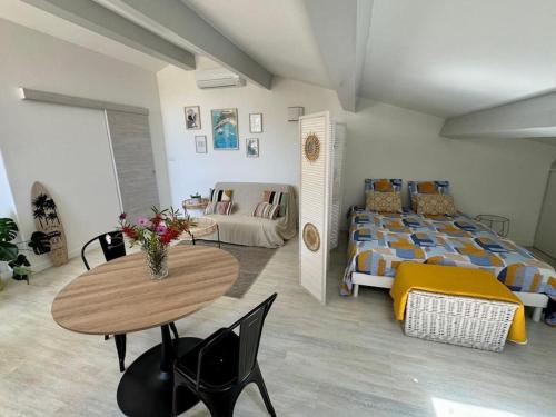 Cette chambre comprend un lit, une table et un canapé. dans l'établissement Nid douillet vue mer Hyères, à Hyères