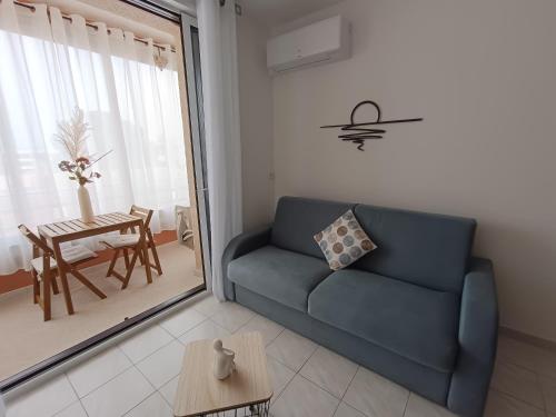 un salon avec un canapé bleu et une table dans l'établissement Le Petit Graulen, au Grau-du-Roi
