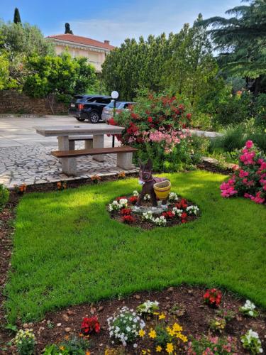 a garden with a bench and flowers in the grass at Katy in Krk