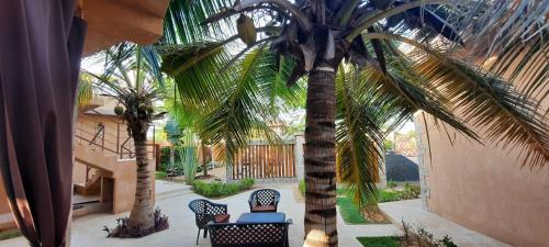a person sitting on a chair under a palm tree at Hôtel La Belle Etoile & SPA in Saly Portudal