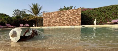 a person is in the water near a swimming pool at Hôtel La Belle Etoile & SPA in Saly Portudal