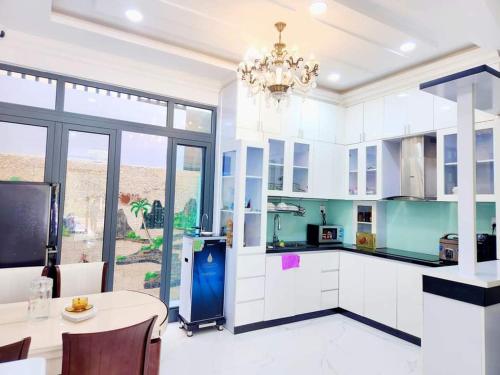 una gran cocina con armarios blancos y una lámpara de araña en Apec Sunsea Condotel Phu Yen en Liên Trì (3)