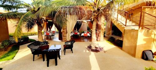 a restaurant with palm trees and tables and chairs at Hôtel La Belle Etoile & SPA in Saly Portudal