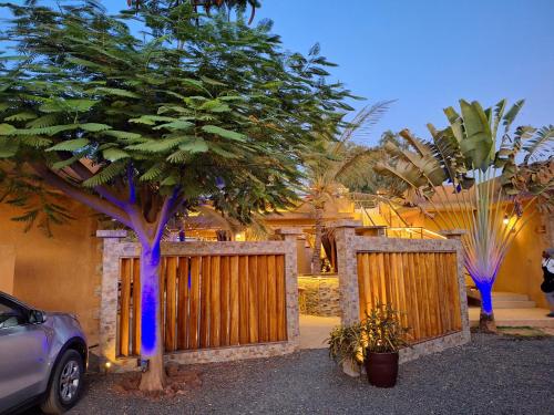 a house with a wooden fence and a tree at Hôtel La Belle Etoile & SPA in Saly Portudal