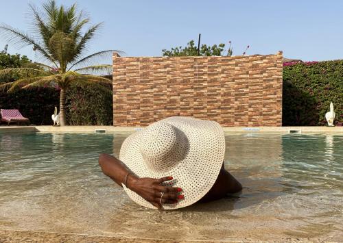 a person sitting in the water wearing a straw hat at Hôtel La Belle Etoile & SPA in Saly Portudal