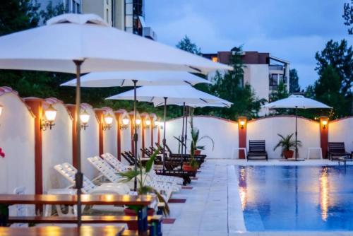 einen Pool mit Tischen, Stühlen und Sonnenschirmen in der Unterkunft APART SUN Travel SUNNY BEACH in Sonnenstrand