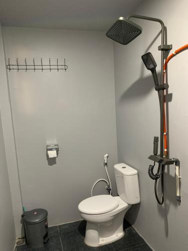 a bathroom with a white toilet and a shower at NASRUL HOUSE HOMESTAY FOR BACKPACKERS in Maros