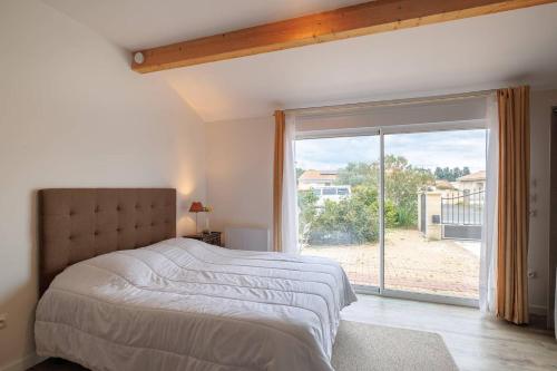 sypialnia z łóżkiem i dużym oknem w obiekcie Les Lilas w mieście Podensac