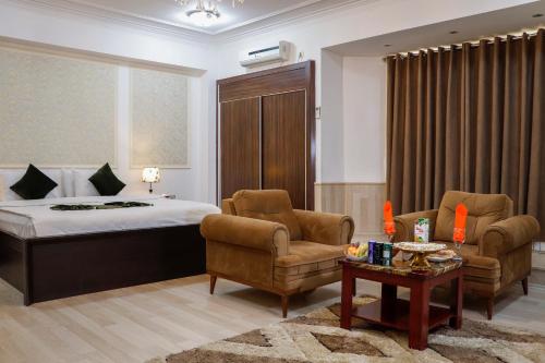 1 Schlafzimmer mit einem Bett, 2 Stühlen und einem Tisch in der Unterkunft Arg Hotel in Herat