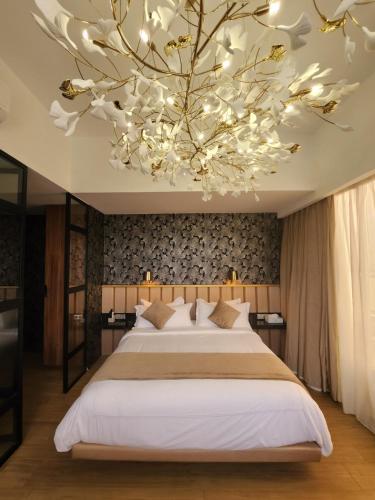 una camera da letto con un grande letto e un lampadario a braccio di Appartements Lamblin a Abidjan