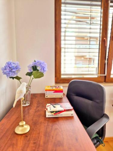 a desk with a chair and a vase of flowers and books at Amsterdam Apartment Strumica in Strumica