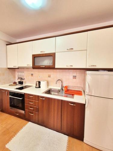 a kitchen with white cabinets and a sink and a refrigerator at Amsterdam Apartment Strumica in Strumica