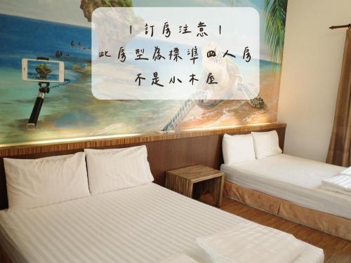 2 letti in una camera con un dipinto sul muro di Koppie Inn a Xiaoliuqiu