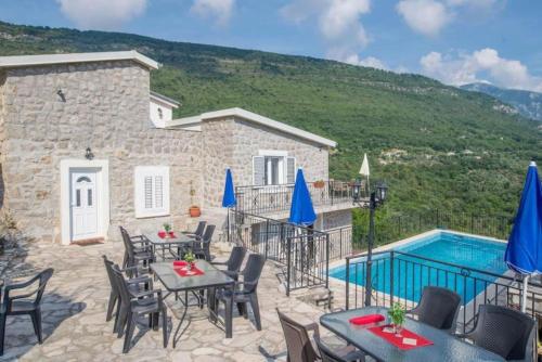 un patio avec tables et chaises et une piscine dans l'établissement Palmagora Villas, à Tivat