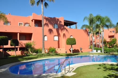 a swimming pool in front of a building with palm trees at Apartment in Marbella in Marbella