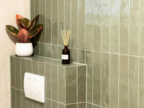 a green tiled bathroom with a bottle and a plant at Casa Faria in Stari Grad