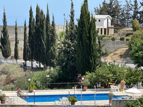 a swimming pool with trees and a building in the background at Chariandry Court in Pissouri