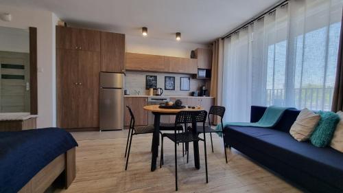 a living room with a couch and a table with chairs at Q Apart Meta -1, 2 lub 3-pokojowe, klimatyzowane apartamenty przy Manufakturze z garażem lub parkingiem Gratis, FV in Łódź