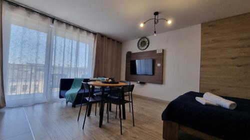 a living room with a table and a bedroom at Q Apart Meta -1, 2 lub 3-pokojowe, klimatyzowane apartamenty przy Manufakturze z garażem lub parkingiem Gratis, FV in Łódź
