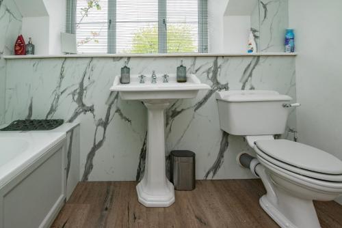 Baño blanco con aseo y lavamanos en Stable Cottage en Ilminster