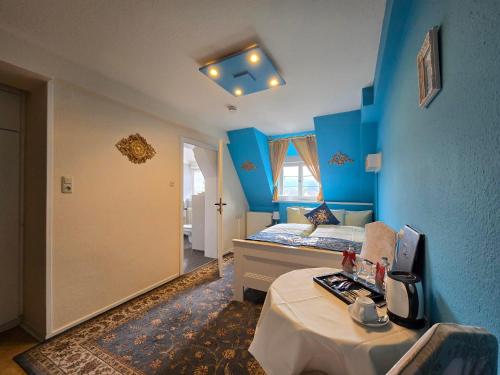 a bedroom with blue walls and a bed with a table at Hotel & Café Schachtenburg in Schlitz