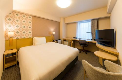 a hotel room with a bed and a desk and a television at Richmond Hotel Aomori in Aomori