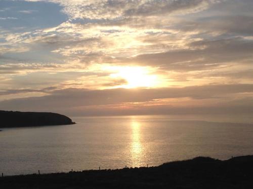 a sunset over a body of water with the sun at Cosy bijou retreat in Pembrokeshire