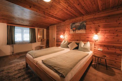 1 dormitorio con 1 cama grande en una habitación de madera en Pension Andrea, en Fusch an der Glocknerstrasse