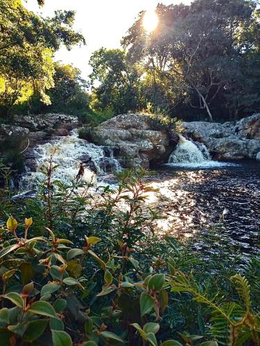 a river with rocks and trees and the sun shining at Reserva do Bosque Hospedaria e Natureza in Ibicoara