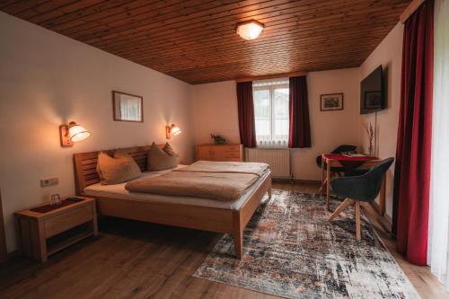 a bedroom with a bed and a desk in it at Pension Andrea in Fusch an der Glocknerstraße