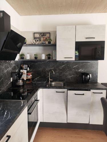 a kitchen with white cabinets and a black counter top at Casa Tara in Döbriach