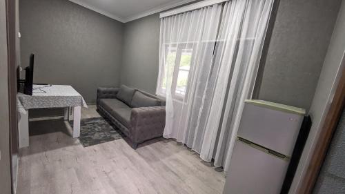 ein Wohnzimmer mit einem Sofa, einem Tisch und einem Fenster in der Unterkunft Guest House NINI in Bordschomi