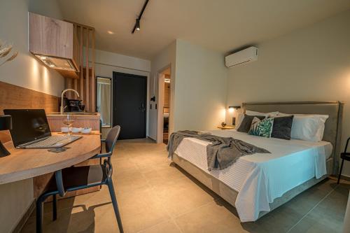 a bedroom with a bed and a desk with a laptop at Luaz Suites in Volos