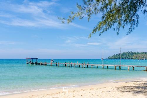 a beach with a pier and people on the water at Seafar Resort in Ko Kood