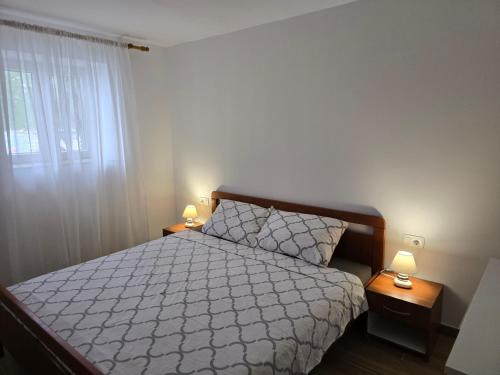 a bedroom with a bed and two night stands with lamps at Apartments Marinko in Janjina
