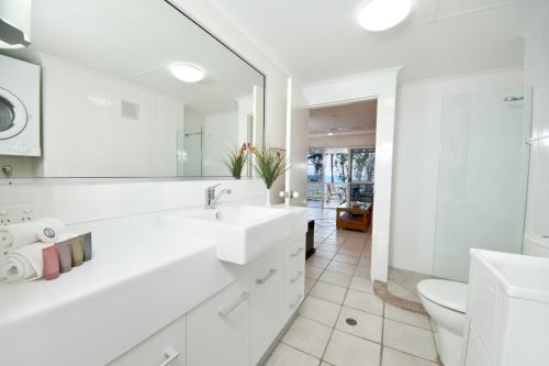 a white bathroom with a sink and a toilet at On Palm Cove Beachfront Apartments in Palm Cove