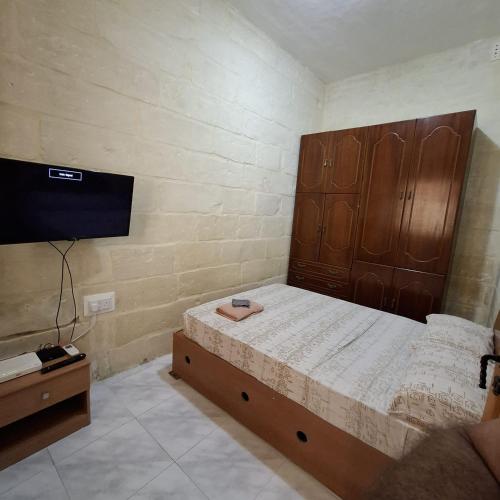 Schlafzimmer mit einem Bett mit einem großen Kopfteil aus Holz in der Unterkunft Three Apartment in Vittoriosa