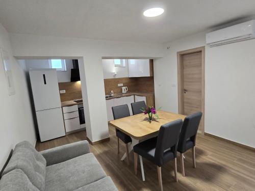 a dining room with a table and chairs and a kitchen at Apartments Marinko in Janjina