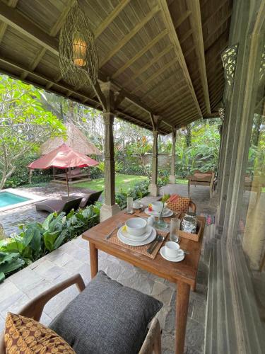een terras met een tafel en stoelen en een zwembad bij Thani Villa Ubud in Ubud