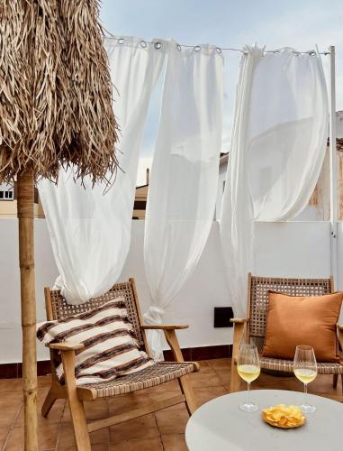 um pátio com 2 cadeiras e uma mesa com copos de vinho em Casita 10 Málaga, holiday home with roof terrace em Málaga