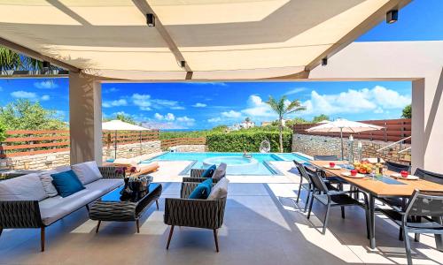 a patio with a couch and a table and a pool at Minoas Villas Heated Pool in Kournás