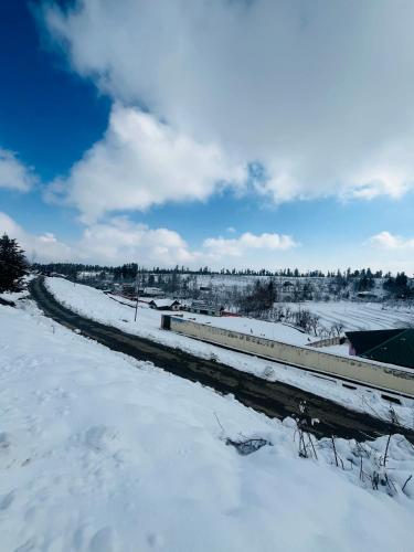 a snow covered road next to a train station at The Cherry Woods in Tangmarg