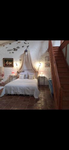 une chambre avec un lit blanc à baldaquin dans l'établissement Les semailles, à Saint-Nazaire-de-Ladarez