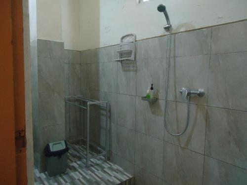 uma casa de banho com chuveiro e cabeça de chuveiro em Kenari Diwang em Ubud