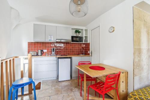 une petite cuisine avec une table et des chaises rouges dans l'établissement Top Appartement avec Wifi - Proche Paris & Métro - R6, à Montreuil