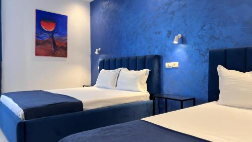- 2 lits dans une chambre aux murs bleus dans l'établissement Hotel RivierA, à Durrës