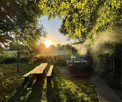 a picnic bench in a field with a hot tub at Elessar Yurt Village in Chichester