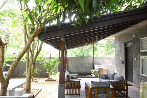 a patio with chairs and a couch under awning at Dollyz Home - Sri Lanka in Ambalangoda